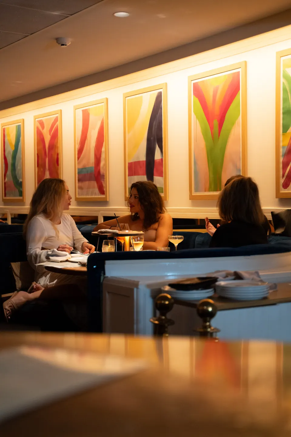Diners at white-clothed tables beneath colourful framed prints at Pelicano