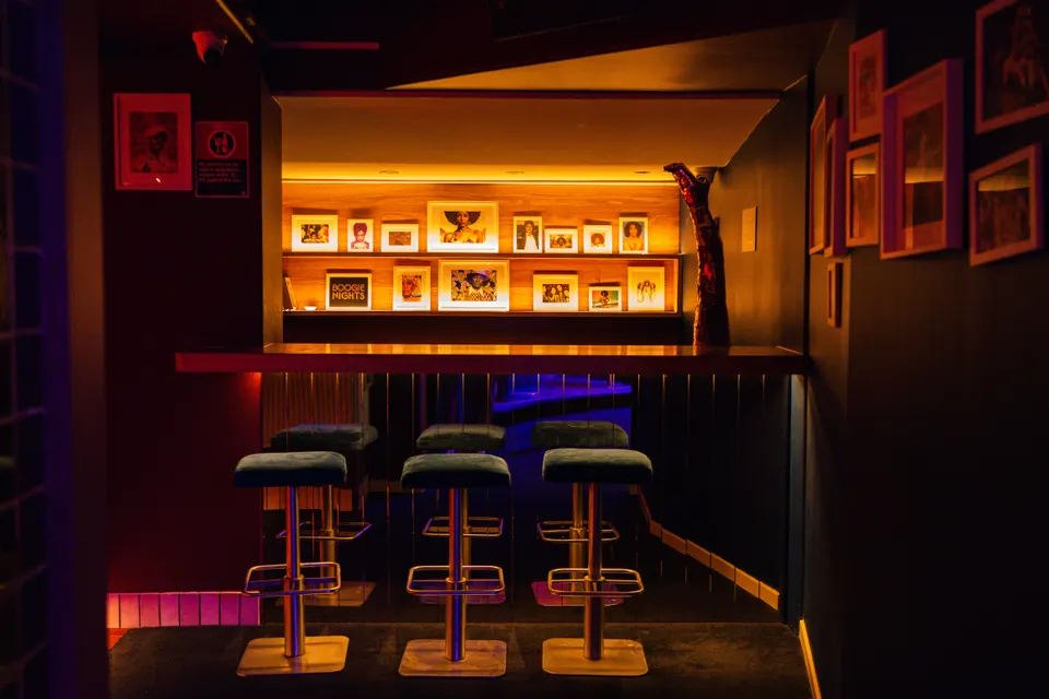 Terrace bar with velvet stools beneath a wall of framed artwork